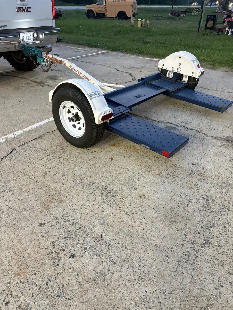 White Master Tow car dolly with navy ramps, hitched to a pickup